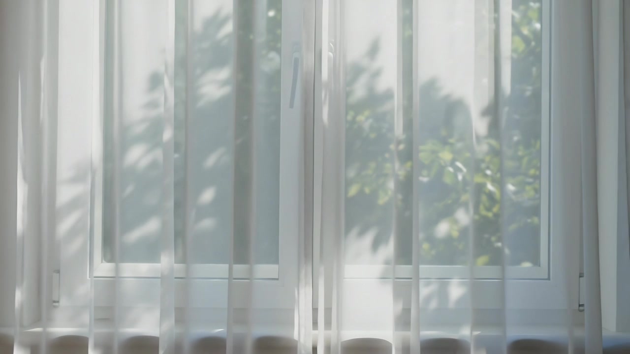 自宅の白い窓辺で揺れる薄手のカーテン、そよ風が葉を揺らし、動く影を落としている。