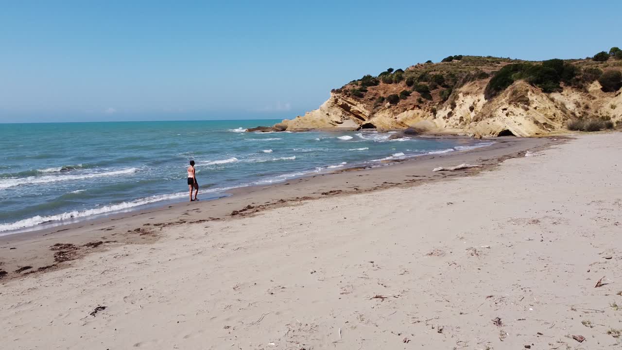 mujer camina en la playa de arena de porto novo en zvernec, vlore, albania - control deslizante