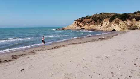 woman walks at sandy porto novo beach in zvernec, vlore, albania - slider