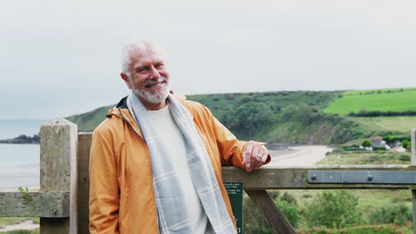 portrait of active senior man walking along coastal path in fall or winter