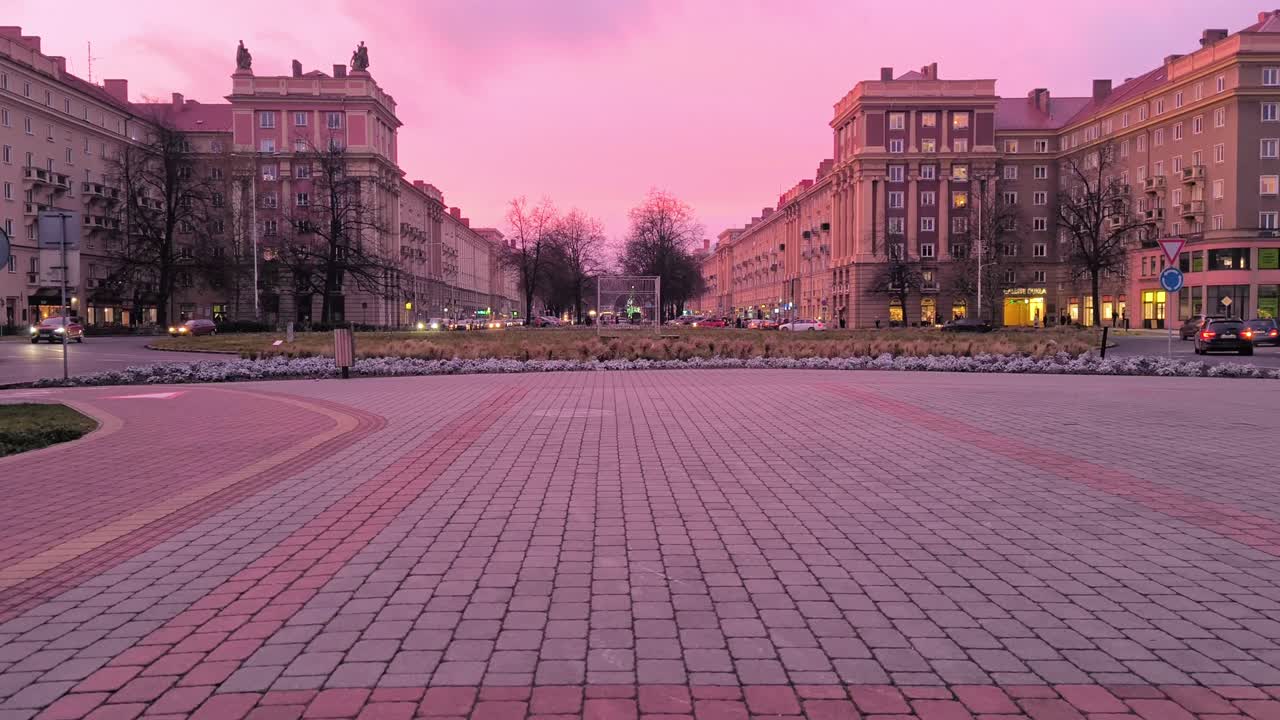 Просторная городская площадь, окруженная монументальными жилыми зданиями социалистической эпохи, во время красочного заката в Остраве-Порубе, Чехия. Спокойная вечерняя атмосфера с исторической городской архитектурой.