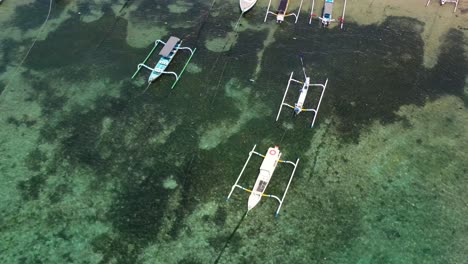 antena de arriba hacia abajo de barcos de pesca en aguas turquesas en la playa de padangbai en bali, indonesia