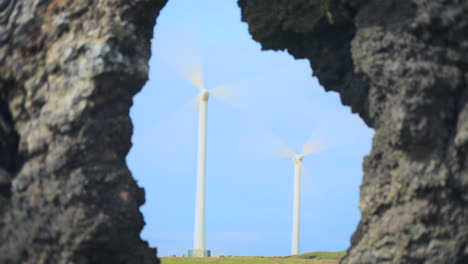 Windmühlen-Drehen-Sich-Im-Sonnenschein,-Umrahmt-Von-Felsformationen