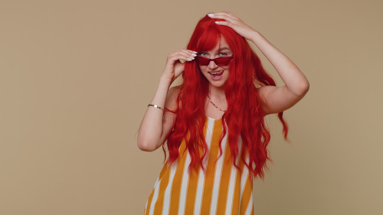 재미있는 빨간 머리 소녀는 장난스러운 어리석은 얼굴 표정을 하고, 미소를 지르고, 혀를 보여주는 농담을 합니다.