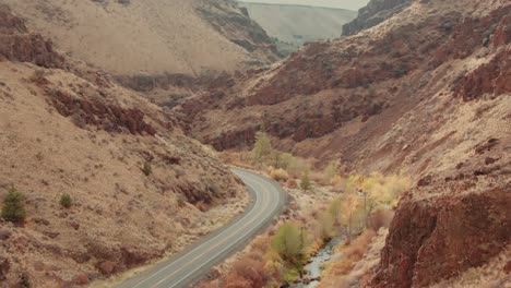 4k aerial red canyon with country road drone dolly out + tilt down