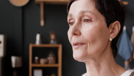 a mature woman drinking a beverage in her kitchen
