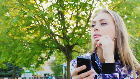 attractive woman listening to music in the park she headphones spring outdoors hd video