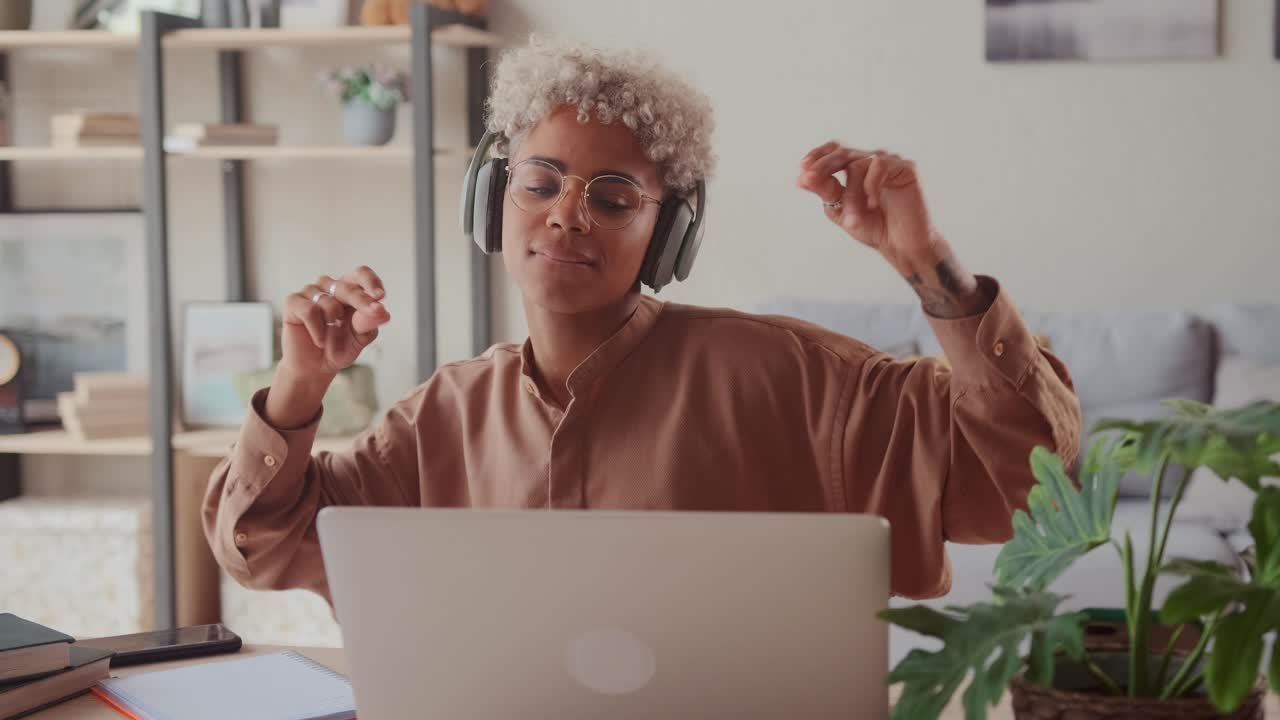 Happy african female in eyeglasses listening choice music in wireless headphones