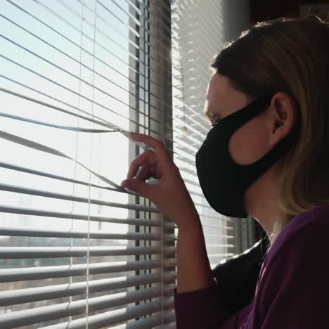 stay at home - a woman peeks out of a window during quarantine and self-isolation