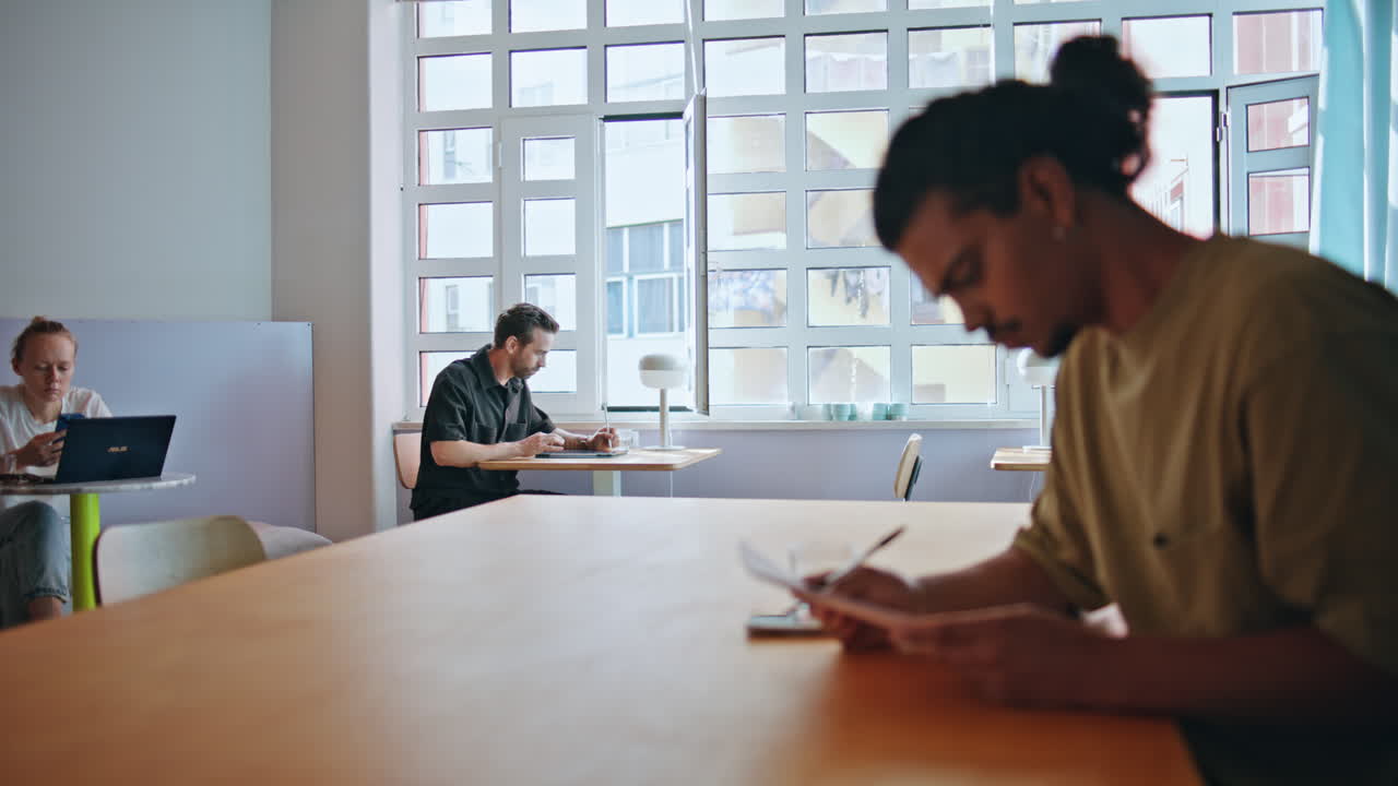 Relaxed cafe visitors sitting tables enjoying calm atmosphere. People working