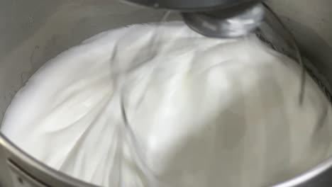 Pastelería-De-Crema-De-Mantequilla-De-Merengue-Suave-Y-Esponjosa-En-Progreso,-Ajuste-De-Cocina-Comercial-Toma-De-Primer-Plano-De-Una-Batidora-Eléctrica-Que-Mezcla-Clara-De-Huevo-Y-Azúcar-Hasta-Que-Es-Un-Pico-Brillante-Y-Un-Pico-Rígido