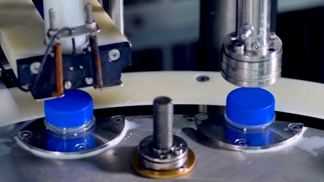 las tapas de las botellas de leche azules son retorcidas por una máquina de fábrica.
