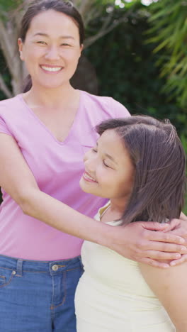 vertical video of happy biracial mother and daughter in garden