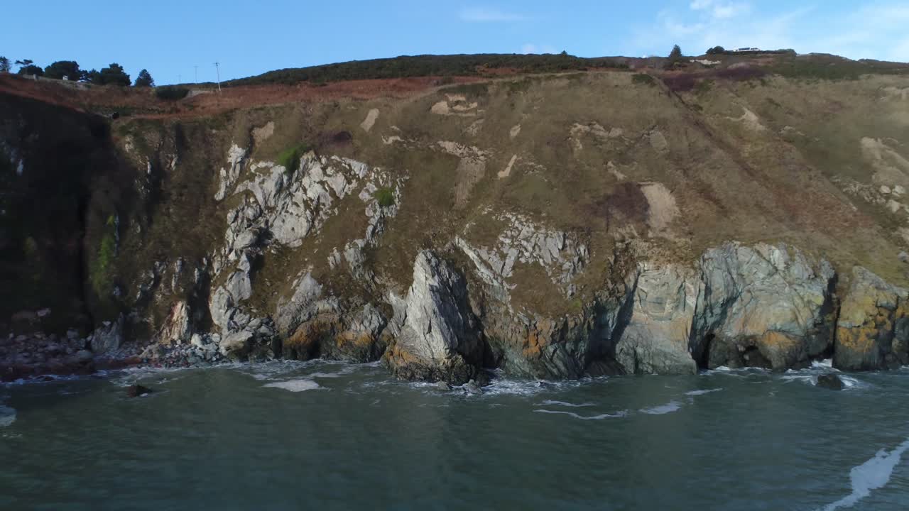 Pan out shot of a vast cliff as the sea crashes against the rocky terrain