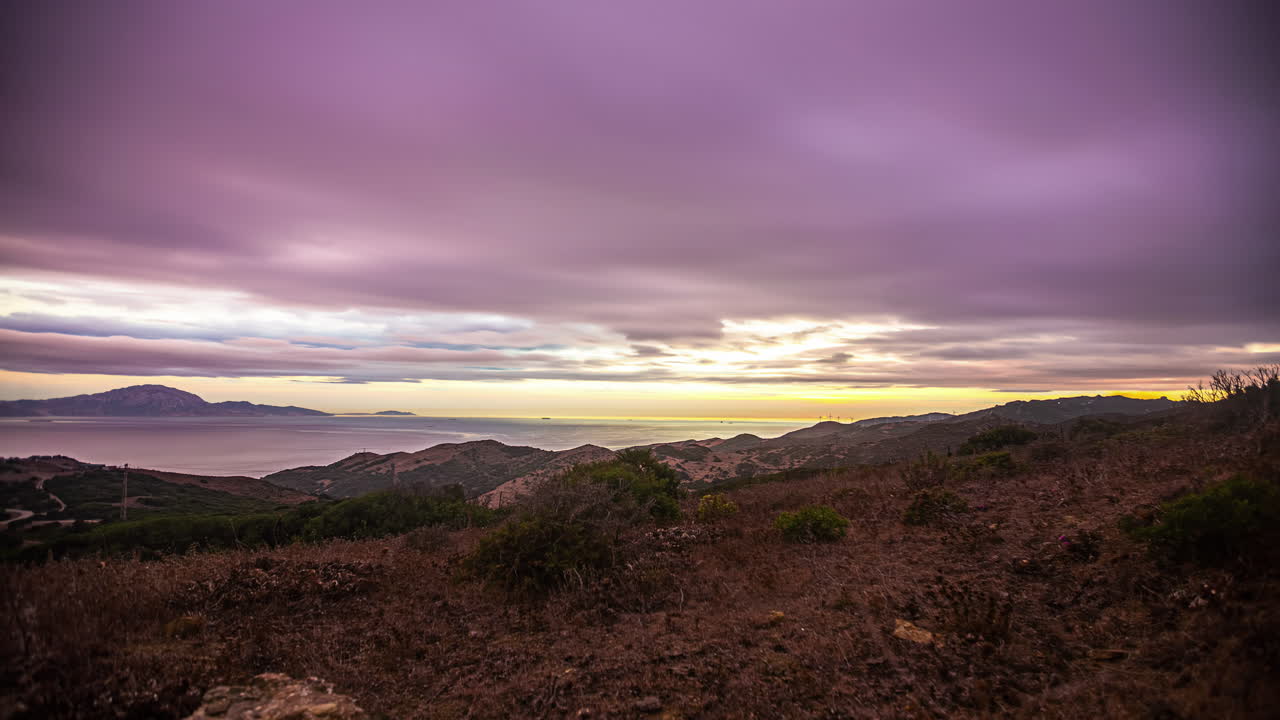 una toma de lapso de tiempo de la puesta de sol en un clima nublado en un paisaje costero