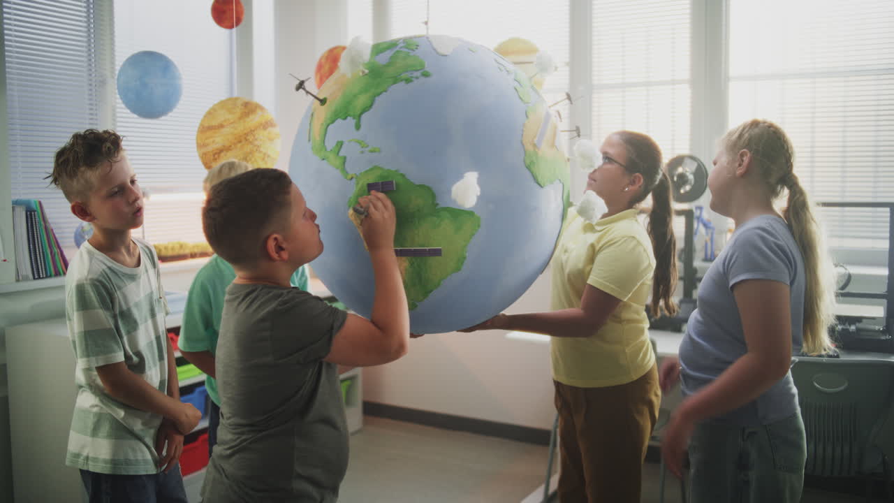 Primary School Children Attaching Miniature Clouds and Wind Turbines to Earth Model