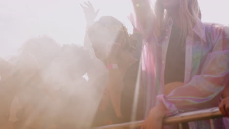 group of young friends dancing behind barrier at outdoor music festival