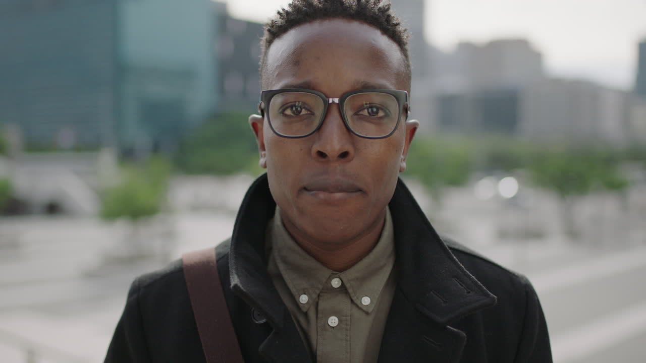 retrato en primer plano de un joven feliz hombre afroamericano estudiante sonriendo alegremente a la cámara con gafas en la ciudad