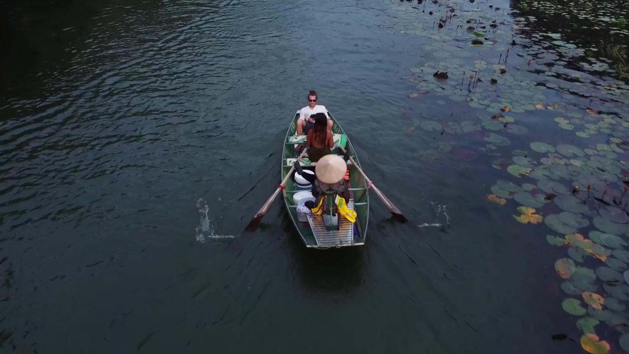Woman paddles with her feet, two tourists on a river with lotus water lily