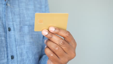 la mano de un hombre con una tarjeta de crédito de oro