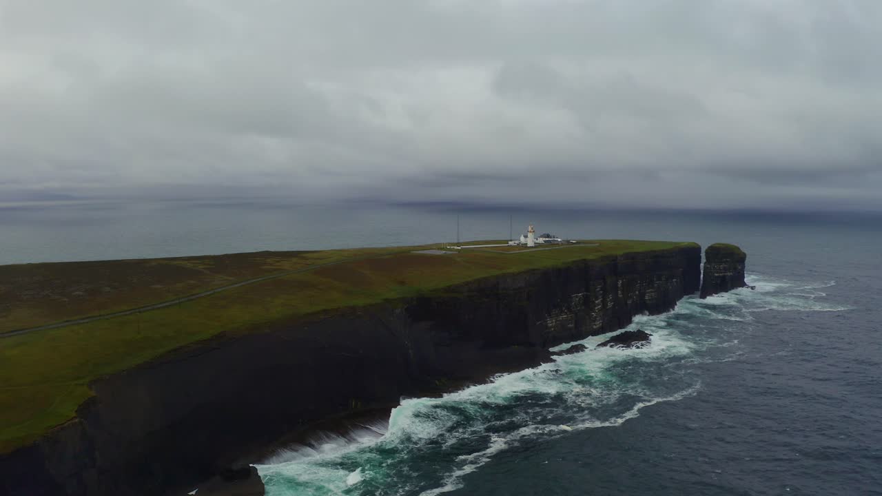 la órbita aérea revela la grandeza de la península de loop head con el faro y la pila de mar distante