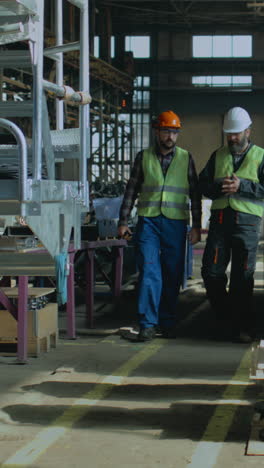 two workers in safety gear walking through an industrial facility