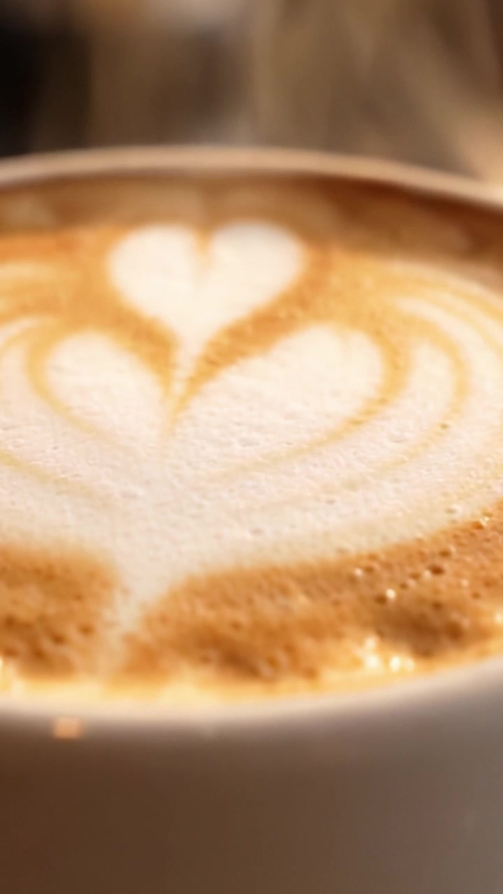 Una Dimostrazione Artistica delle Abilità del Barista: Una Tazza di Caffè Splendidamente Preparata con Intricata Latte Art che Presenta Disegni a Cuore e Schiuma Cremosa