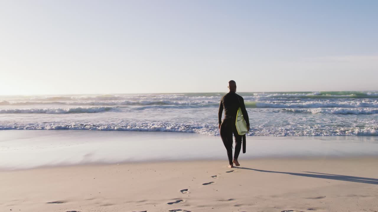 시니어 아프리카계 미국인 남자가 해변에서 서프보드와 함께  ⁇ 고 있습니다.