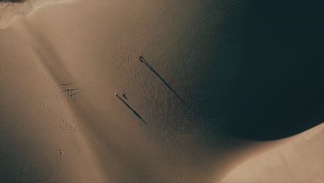 people walking over sand dunes seen from above