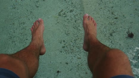 man's feet over water in french polynesia. sunny day