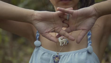 Cinematic-slow-motion-shot-of-a-fashion-model-cracking-her-fingers-in-slow-motion-while-wearing-a-blue-and-white-dress-and-a-necklace-in-the-tropical-rainforest-of-Goa-India,-Slomo