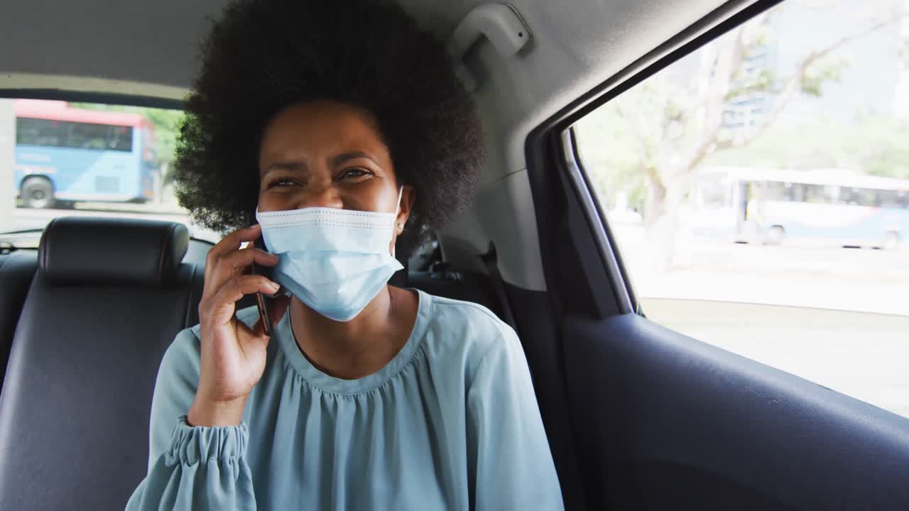 Afroamerikansk forretningskvinde med ansigtsmaske taler i smartphone