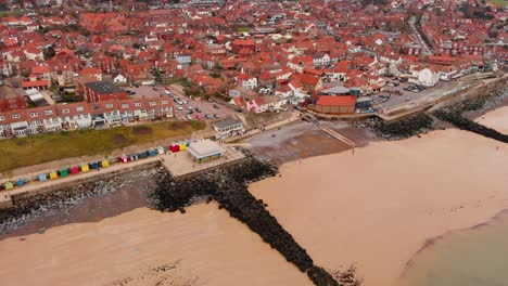 Aerial---Seawall-and-coast-on-North-Sea,-Sheringham,-England,-wide-spinning-shot