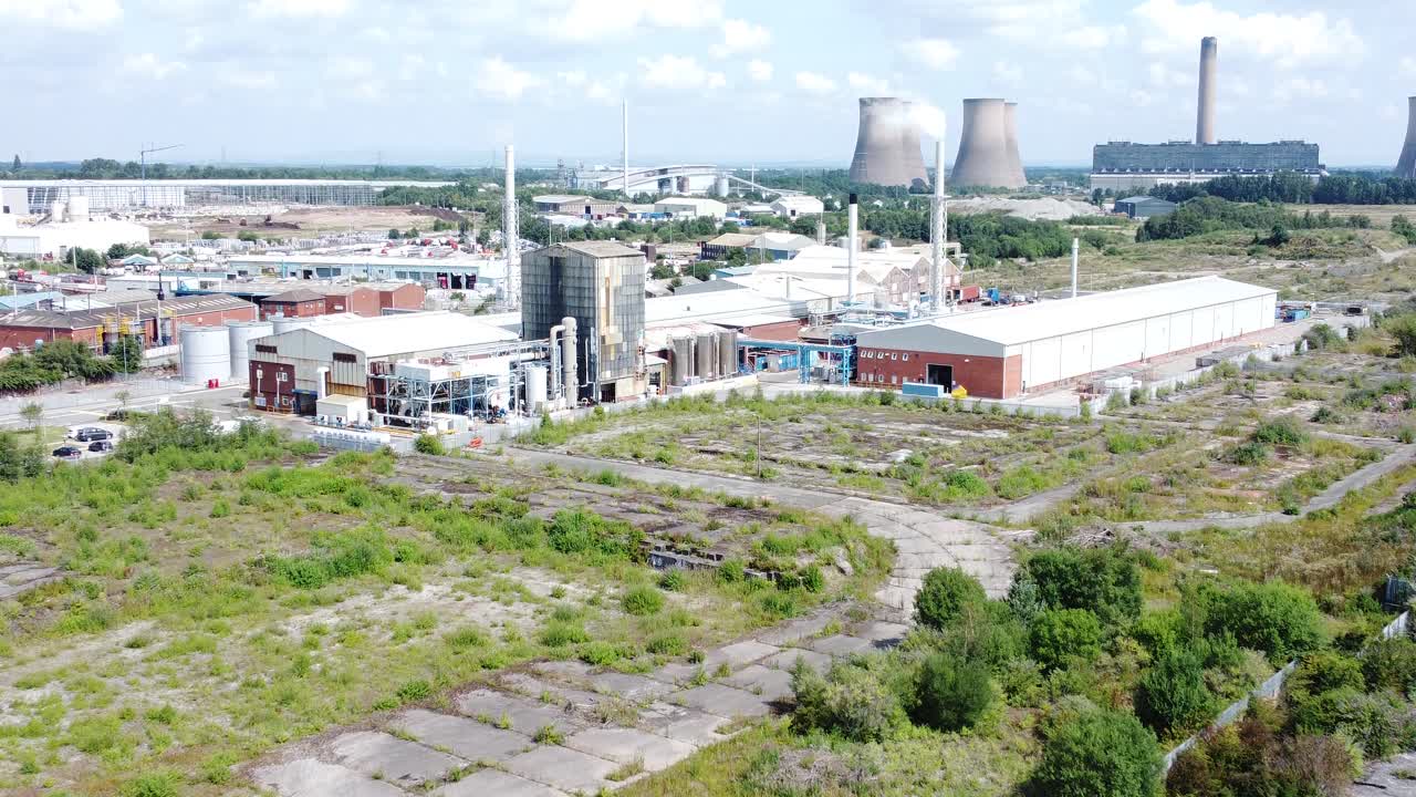 Industrial warehouse power plant refinery buildings under smokestack wasteland aerial view zoom in