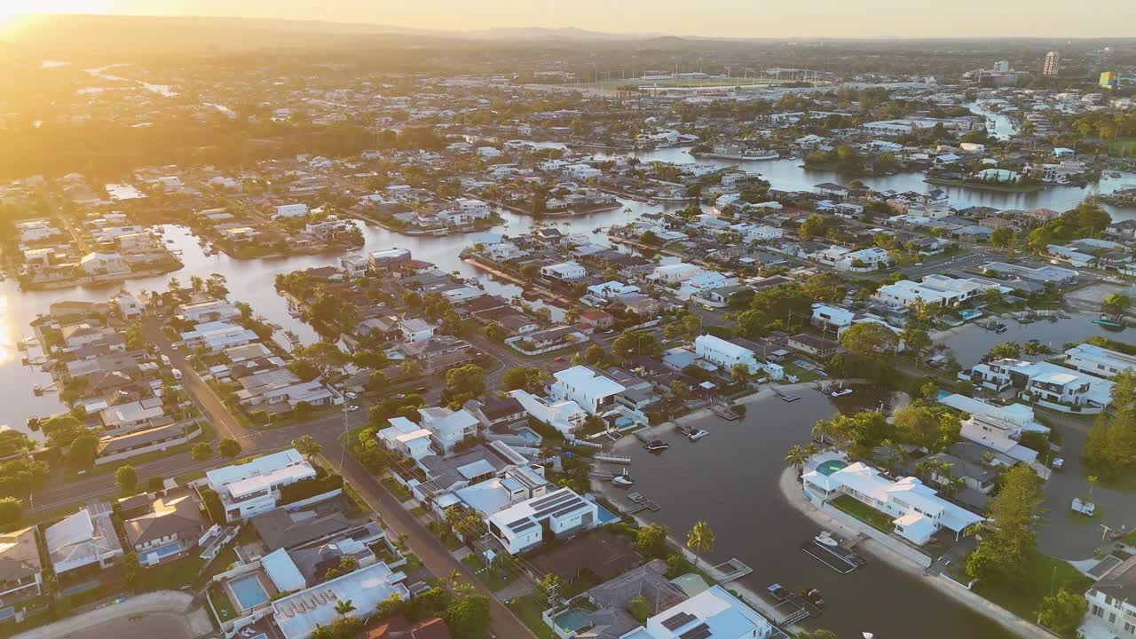 Drone captures Gold Coast's suburban landscape and waterways during a vibrant sunset, highlighting urban beauty and natural harmony