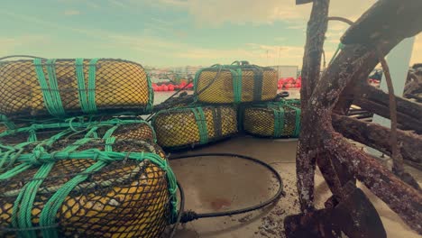 Fishing-gear-rests-on-the-moist-asphalt-in-a-coastal-town-of-Spain,-including-metal-anchors-and-nets,-representing-the-core-of-maritime-livelihood-and-coastal-heritage