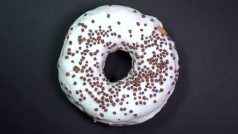 tasty and fresh sprinkled donut close-up macro shot spinning on a black background.