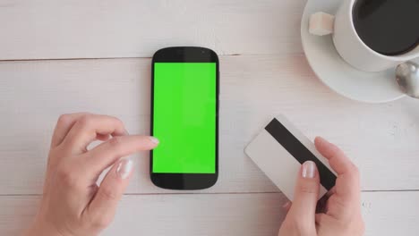 close-up of a woman's hand drinking coffee and using a green-screen phone