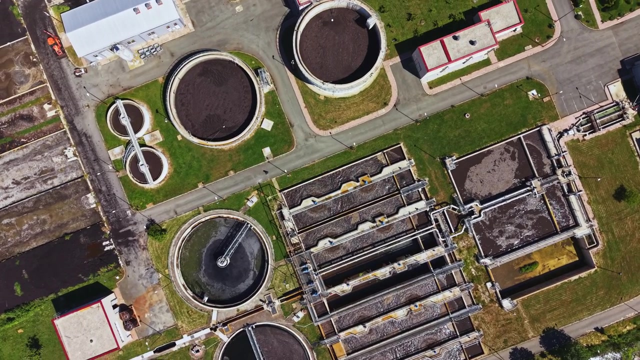Industrial site with water facilities. Drones capture sewage processing complex details. Urban water treatment structures observed from aerial perspective clearly