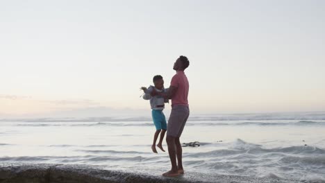 African-american-father-carrying-his-son-on-sunny-beach