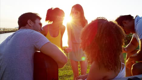 multi ethnic people enjoying beach party with guitar