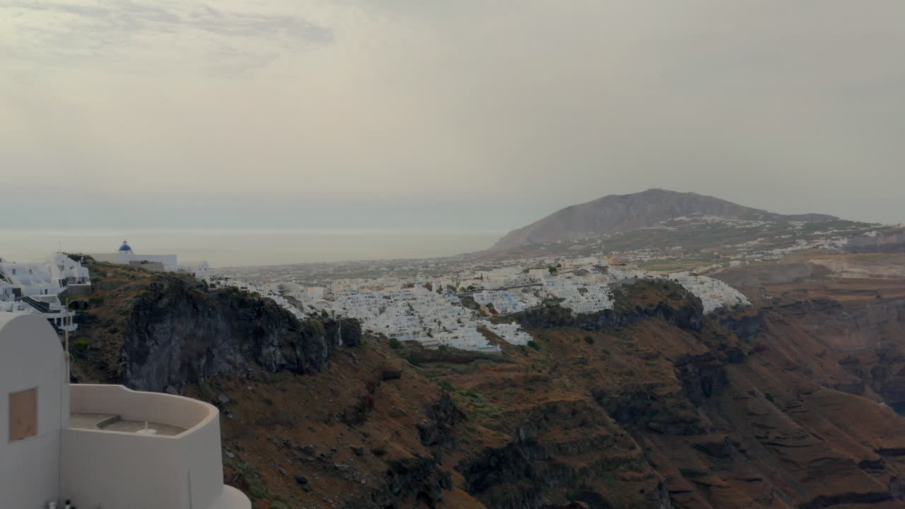 antena: vista panorámica de fira en santorini, grecia durante el amanecer nublado