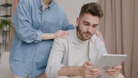 man using the tablet sitting on sofa