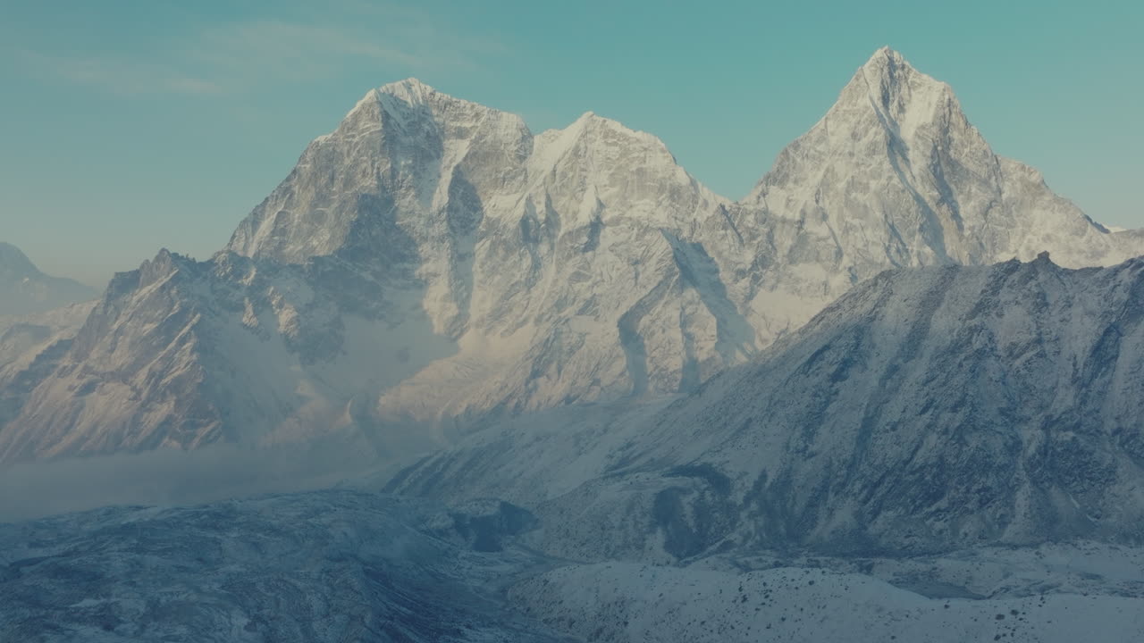 Drone shot of Everest Base Camp trek in Khumbu, Nepal. Morning snowfall reveals Khumbu Glacier with Cholatse Gokyo Peak in the Himalayas, a majestic cold-weather view glowing under sunlight, travel