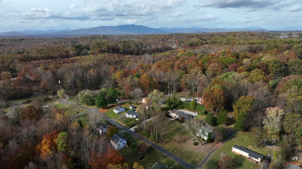Colored suburb neighborhood in autumn season. Straight street with single family homes and houses. Aerial top down shot.