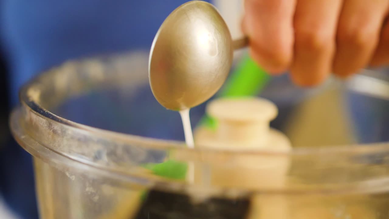 큰 스푼에서 파이를 굽는 푸드 프로세서에 우유를 붓는 것