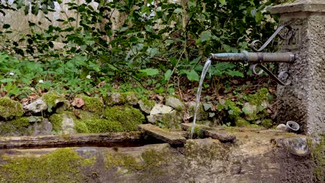 natural old idyllic water well fountain on a hiking trail in europe during sunny day