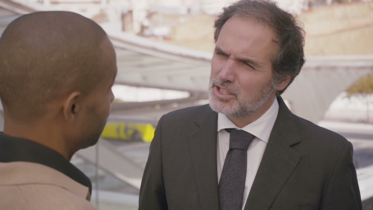 자신감 있는 성숙 한 사업가 가 도시 에서 동료 와 대화 하고 있다