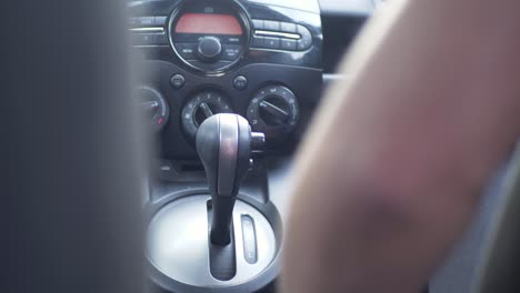 Slow-motion-shot-of-driver's-hand-pulling-lever-gearbox-handbrake-in-car-automobile-reverse-park-vehicle-transmission-console-driving-transport-travel