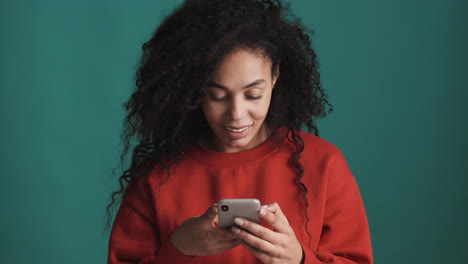 Mujer-Afroamericana-Usando-Un-Teléfono-Inteligente-Sobre-Fondo-Azul.